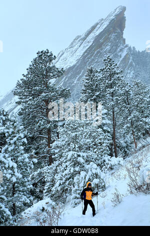 Snowshoer trekking sotto Flatiron ricoperta di neve, Boulder, Colorado, STATI UNITI D'AMERICA Foto Stock