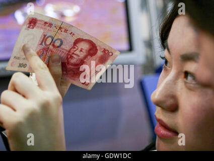 Un cassiere verificare un centinaio di banca nota di Yuan Renminbi o Foto Stock