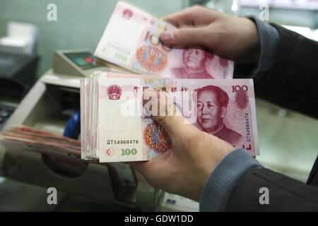 Un cassiere verificare un centinaio di banca nota di Yuan Renminbi o Foto Stock