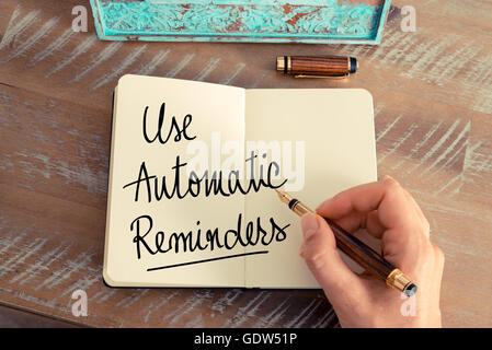 Il testo scritto a mano utilizzare promemoria automatici come concetto di immagine. Effetto retrò e tonico immagine di una donna la scrittura a mano una nota con la penna stilografica su un notebook. Foto Stock