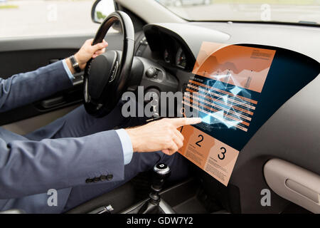 Uomo alla guida di auto e rivolto verso il computer di bordo Foto Stock