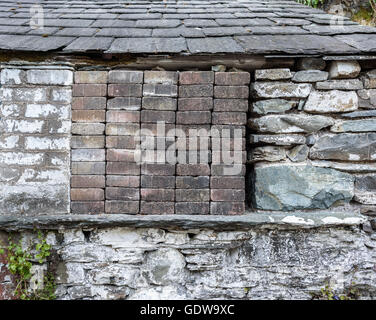 Un vecchio fienile finestra bloccato con piccoli mattoni. Foto Stock