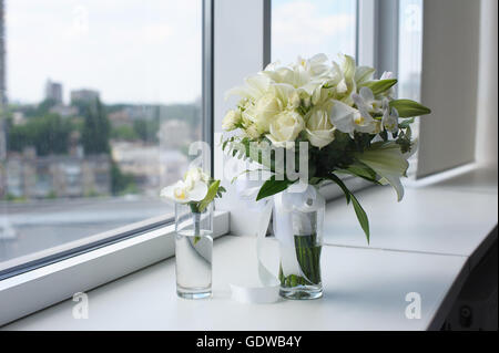 Bellissimo mazzo di nozze in un vaso di vetro. I fiori sul davanzale bianco. Boutonnière in un piccolo vaso. Foto Stock