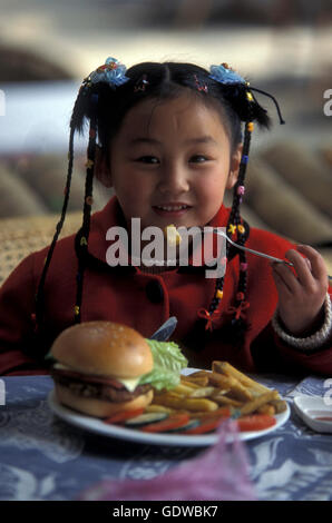 Una ragazza con un hanburger in un ristorante della città di Yangshou nei pressi della città di Guilin nella provincia del Guangxi in Cina Foto Stock