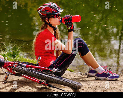 Ciclismo ragazza indossando il casco di bere acqua in bottiglia. Foto Stock