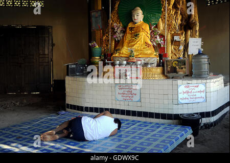 Uomo dorme nella parte anteriore della statua del Buddha Foto Stock