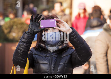 Una donna usa il suo cellulare per scattare foto su una strada Foto Stock