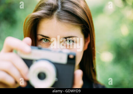 Felice i Capelli rossi ragazza caucasica donna giovane fotografo fotografare il vecchio Retro Vintage fotocamera a pellicola in estate Fores verde Foto Stock