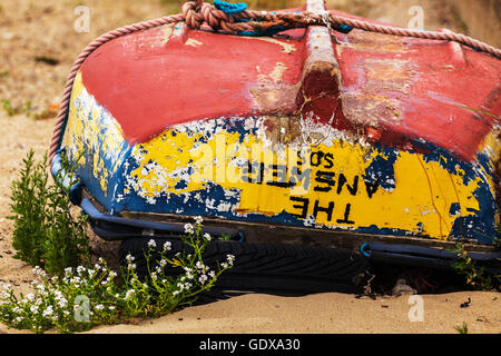 Vecchio Dinghy giacente capovolto sulla spiaggia Foto Stock