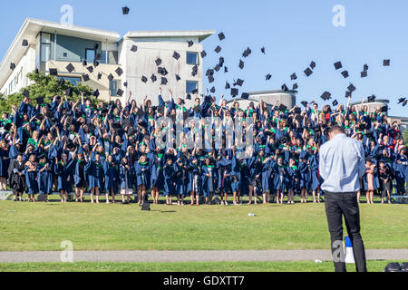 Laurea studenti aventi foto di gruppo gettando mortarboard cappelli in aria Foto Stock