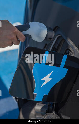 Immagine a colori di una mano di un uomo la preparazione per caricare un auto elettrica. Foto Stock