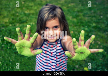 Bambina con le mani dipinte di verde con chalk dopo il disegno; profondità di campo Foto Stock