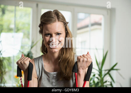 Ritratto di una giovane donna che esercitano nel soggiorno, Monaco di Baviera, Germania Foto Stock