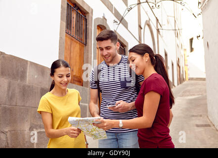 Turista giovane in vacanza con uno zaino e mappa chiedere indicazioni in una strada stretta mentre vestita casualmente in jeans e Foto Stock