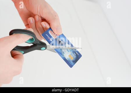 Donna mani il taglio di un azzurro carta di credito con forbici isolati su sfondo bianco Foto Stock