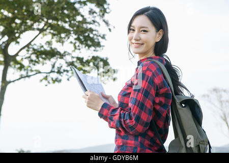 Vista laterale Ritratto di giovane donna sorridente backpacker tenendo una mappa con lo sguardo sul lato anteriore Foto Stock