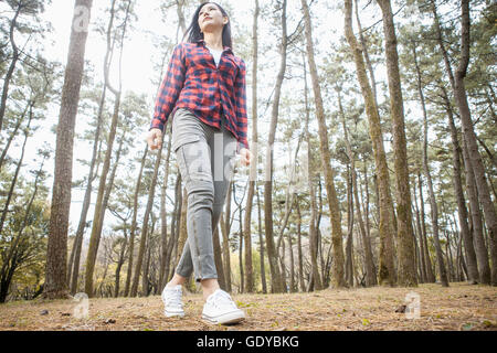 Basso angolo vista della giovane donna passeggiate in foresta Foto Stock