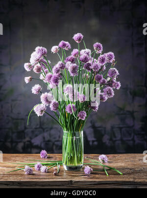 Bouquet di cipolla (erba cipollina) fiori in vaso sul tavolo di legno. Foto Stock