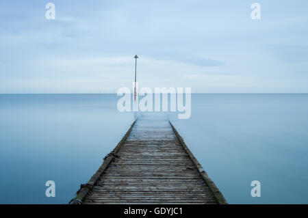 Un molo in legno stretching fuori nella distanza in Galles, UK. Foto Stock