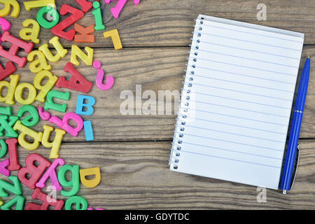 Blocco note e molte lettere sul tavolo di legno Foto Stock