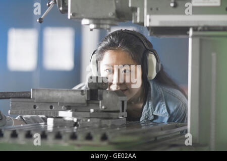 Giovane ingegnere femmina indossa le cuffie e lavorando in un impianto industriale di Freiburg im Breisgau, Baden-Württemberg, Germania Foto Stock