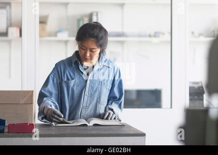 Femmina giovane ingegnere libro di lettura in un impianto industriale di Freiburg im Breisgau, Baden-Württemberg, Germania Foto Stock