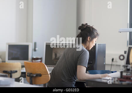 Femmina giovane ingegnere di lavoro sul computer in un ufficio di Freiburg im Breisgau, Baden-Württemberg, Germania Foto Stock