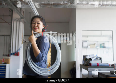 Giovane ingegnere femmina con il tubo sulla sua spalla in un impianto industriale di Freiburg im Breisgau, Baden-Württemberg, Germania Foto Stock