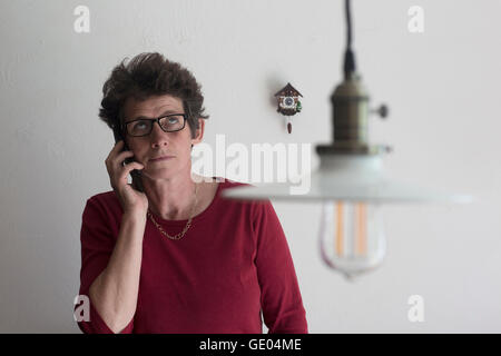 Sconvolto donna matura parlando al telefono cellulare e cercando di Freiburg im Breisgau, Baden-Württemberg, Germania Foto Stock