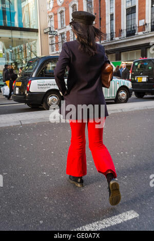Giovani vestiti alla moda donna crossing Street, Londra, Regno Unito Foto Stock
