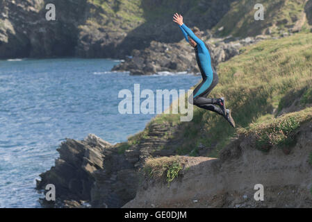 Un adolescente tombstoning off a strapiombo sul promontorio in Newquay, Cornwall. Foto Stock