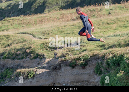 Un adolescente tombstoning off a strapiombo sul promontorio in Newquay, Cornwall. Foto Stock