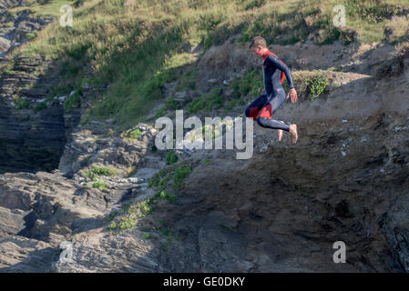 Un adolescente tombstoning off a strapiombo sul promontorio in Newquay, Cornwall. Foto Stock