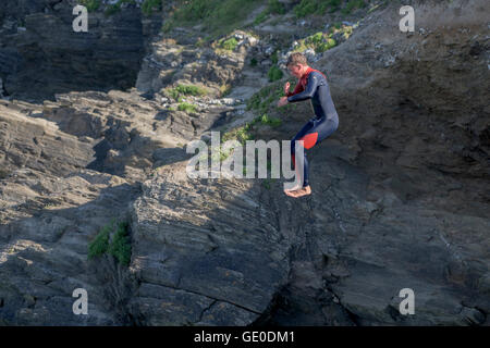 Un adolescente tombstoning off a strapiombo sul promontorio in Newquay, Cornwall. Foto Stock