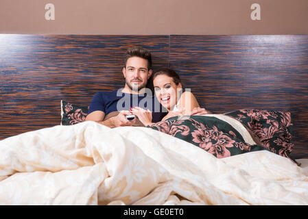 Bella coppia Giovane guardare la TV a letto. Foto Stock