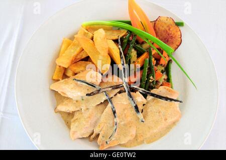 Scaloppine di pollo con salsa alla vaniglia, Spicchi di patate e verdure miste, guarnita con baccelli di vaniglia Foto Stock