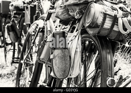 Vecchia bicicletta militare con kitbag e attrezzature. Zaino e contenitori per alimenti e bevande. Scena vintage. In bianco e nero. Foto Stock
