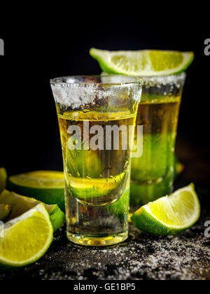 Mexican Gold Tequila con calce e sale sulla tavola nera. Due colpi di Tequila. Bere alcool. Foto Stock