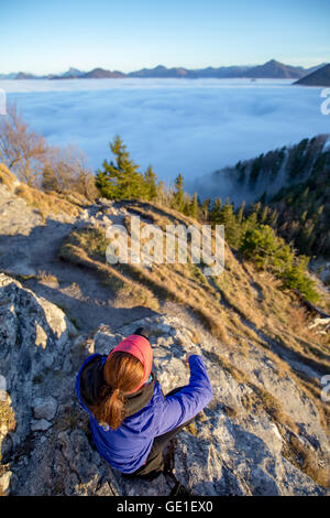 Vista aerea della donna seduta sulla montagna guardando a vista al di sopra delle nuvole, Salisburgo, Austria Foto Stock