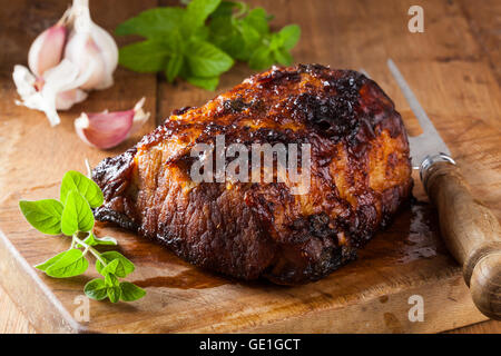 Forno arrosto di lombo di maiale su un tagliere in una cucina rustica. Foto Stock