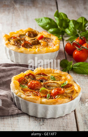 Quiche con pomodori ciliegia su una tavola in legno rustico. Foto Stock