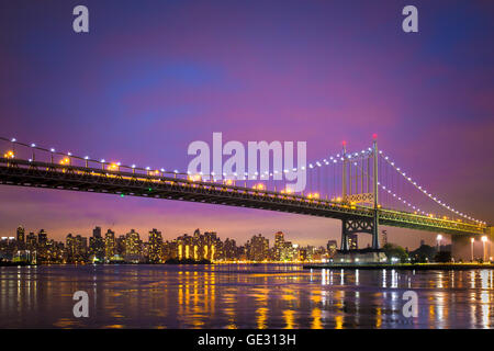 Vista del Robert J. Kennedy RFK bridge in New York City da Astoria Queens a Manhattan visibile appena dopo il tramonto con luci Foto Stock