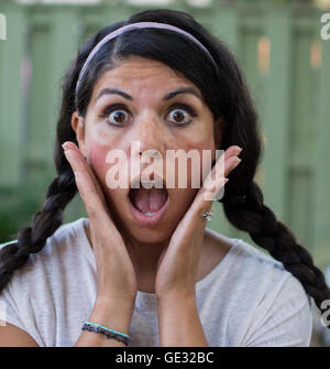 Una donna sorpresa trattiene il suo volto in allarme. Foto Stock