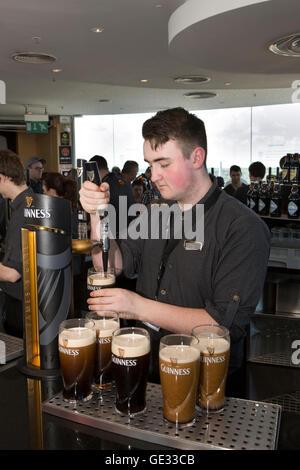 Irlanda, Dublino, Ainsfort Street, Guinness Storehouse, bar Gravity barista versando pinte di Guinness Foto Stock