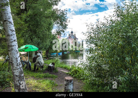Il pittore in stivali in pelle e con un gatto nero sulla canapa richiama un impercettibile albero su altra banca di fiume anche se direttamente prima Foto Stock