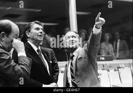 Il Presidente Ronald Reagan è informato dalla JSC Direttore Christopher C. Kraft Jr., che punti verso l'orbiter spotter sui plotter di proiezione nella parte anteriore della missione di controllo delle operazioni in camera il Johnson Space Center Mission Control Center. Questa foto è stata scattata appena prima di uno spazio-terra di conversazione tra STS-2 Membri di equipaggio Joe H. Engle e Richard H. veramente, che erano in orbita intorno alla terra in lo space shuttle Columbia. Credito foto: Foto NASA numero: S81-39499 Data: Novembre 13, 1981 Foto Stock