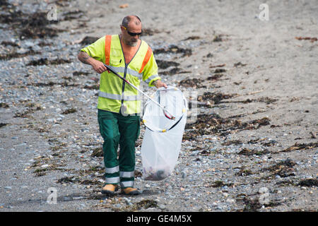 Un uomo, impiegati da Ceredigion County Council autorità locale, lavorando come un selezionatore di lettiera di pulizia nel cestino della spazzatura i rifiuti plastici fuori la spiaggia in Aberystwyth Wales UK Foto Stock