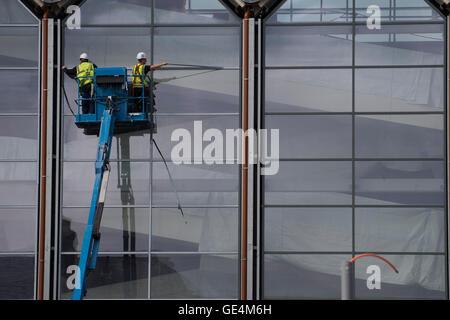 I lavori di costruzione nel Regno Unito: due lavoratori in una posizione elevata 'cherry picker' di lavoro della piattaforma sulla parte esterna di vetri di una nuova Tesco un Marks & Spencer retail outlet, Aberystwyth Wales UK Foto Stock