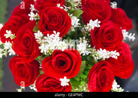 Rose rosse da fiori artificiali e fiori di colore bianco in vaso Foto Stock