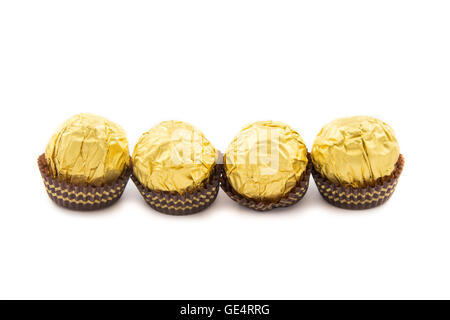 Dolci palline di cioccolato con mandorle avvolte in foglia d'oro carta su sfondo bianco Foto Stock